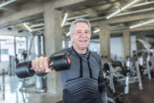 Losing weight and gainiong strength by a dumbell training performed by older man in the fitness center