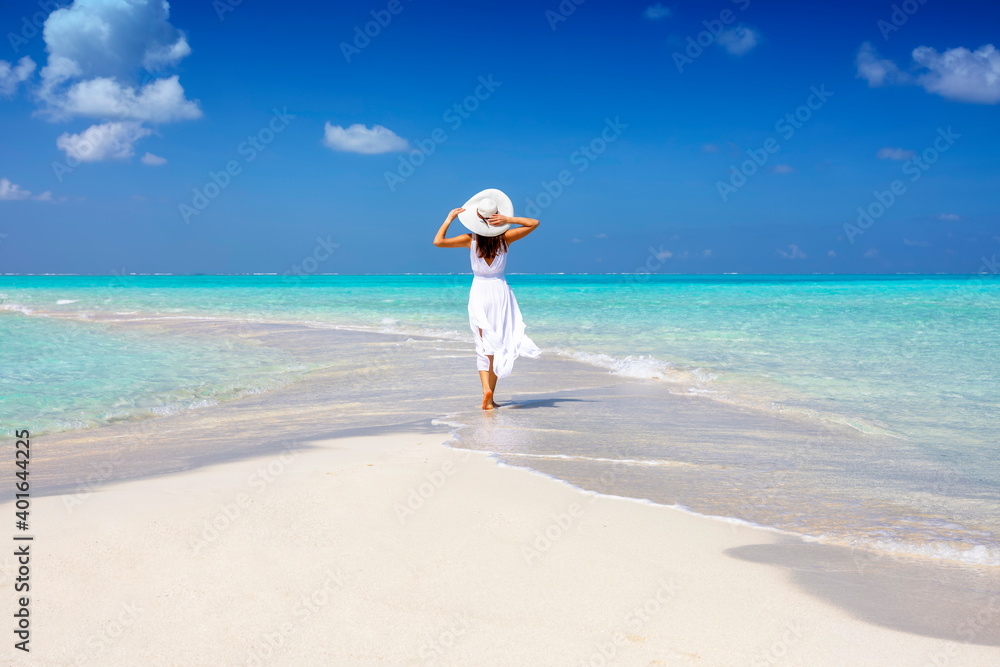 A woman in a white summer dress stands on a sandbar surrounded by turquoise ocean in the Maldives islands - obrazy, fototapety, plakaty 