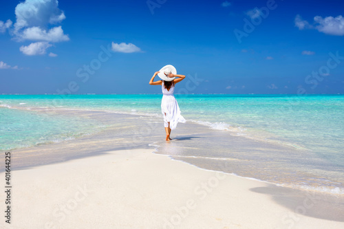 Foto A woman in a white summer dress stands on a sandbar surrounded by turquoise ocea