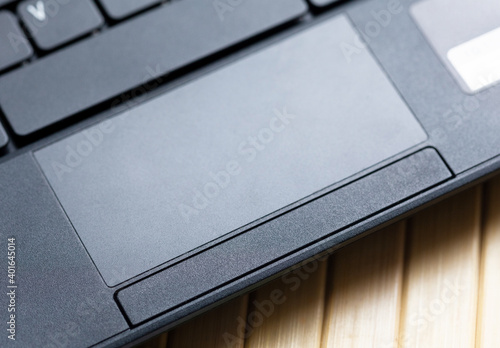 Simple black laptop trackpad, modern touchpad with physical buttons top view, closeup. Netbook track pad top view, from above, up close. Ways of computer digital input, mouse alternative concept