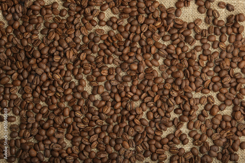 roasted coffee in beans, sprinkled on burlap