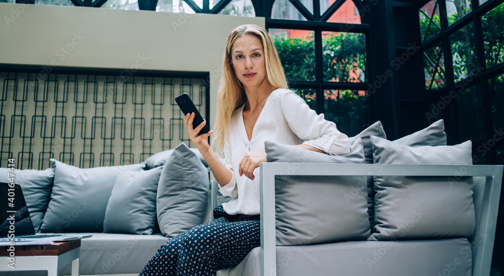Obraz premium Serious female employee using smartphone in cafe