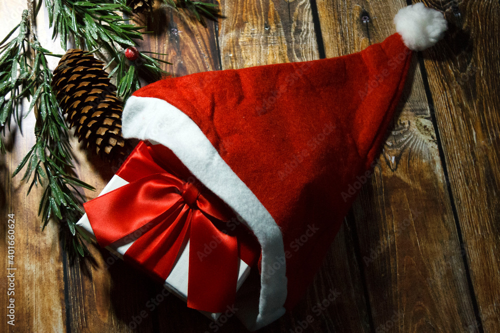 Christmas decoration with present and Santa hat on wooden background