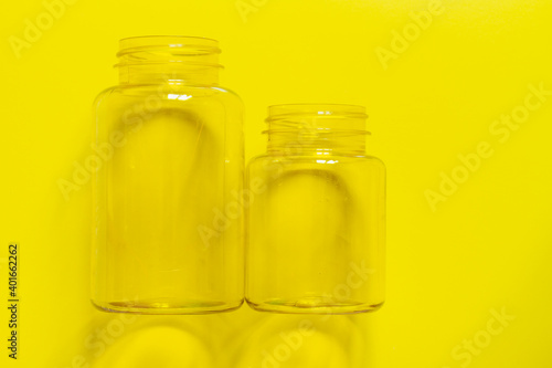 Two transparent plastic empty cans on a yellow background. Copy space.