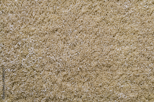 Texture of beige frieze carpet. Artificial wool material carpeting.