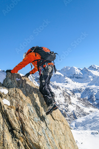 erfahrener Kletterer an einer steilen Felswand im winterlichen Hochgebirge.