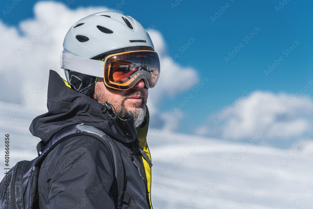 A man with skis stands high in the mountains enjoying the scenery. Go downhill skiing, extreme relaxation