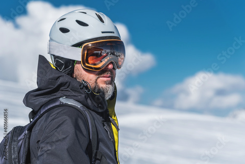 A man with skis stands high in the mountains enjoying the scenery. Go downhill skiing, extreme relaxation