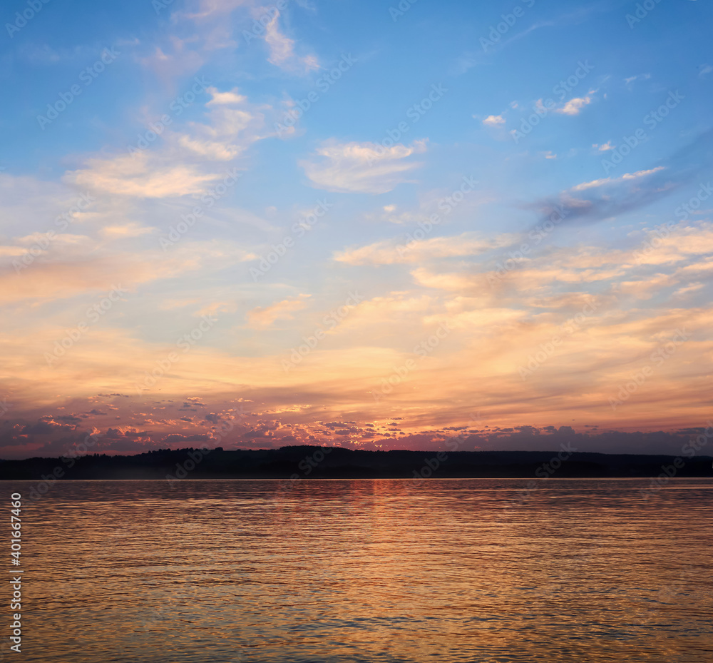sunset sky is reflected in the water against the background of the distant shore