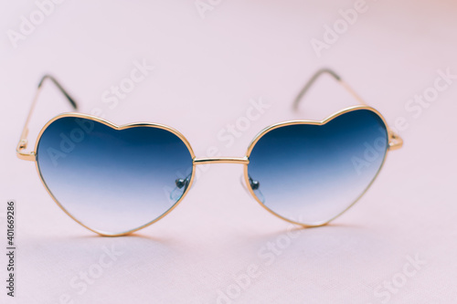 Heart shaped sunglasses on pink background close up
