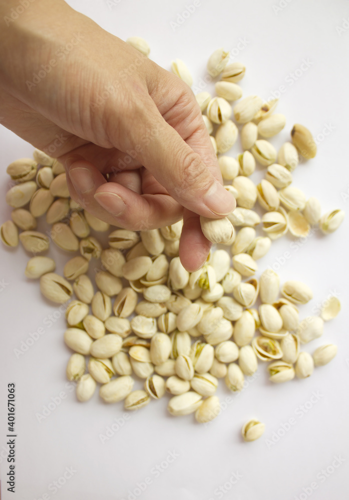 Pistachio nuts and woman's hands. Pistachios isolated on white background, top view. Pistachio nuts and woman's hands. Pistachios isolated on white background, top view.