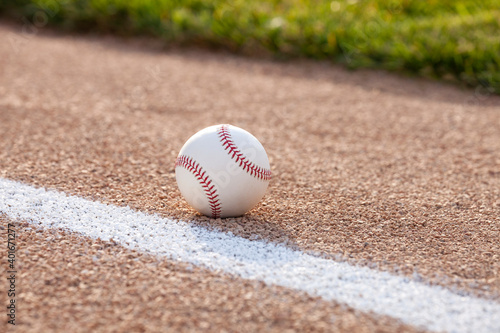 Selective focus low angle view of a baseball on gravel infield near stripe and grass
