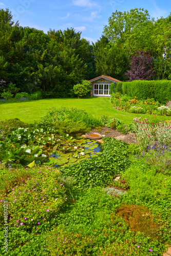 Well-kept garden with a colorful flower bed, garden shed and pond.