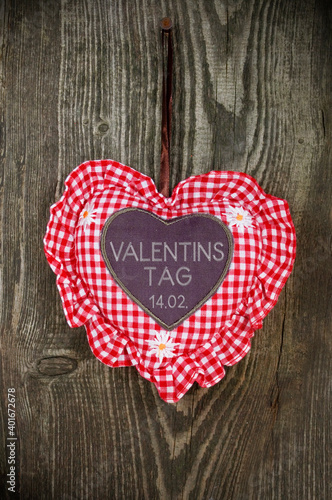 Red and white heart on a weathered wood and valentines day and the german word valentinstag