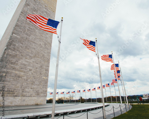 American flags waving in the wind around the Washington Monument in Washington, D.C.