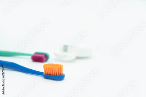 Two colored toothbrushes with bright orange and red bristles and dental floss lie on a white background  daily oral care