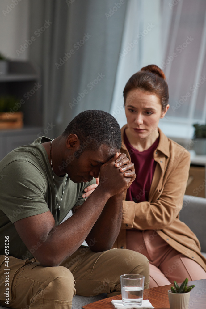 African man worried about his problems with woman sitting near by and supporting him African man worried about his problems with woman sitting near by and supporting him