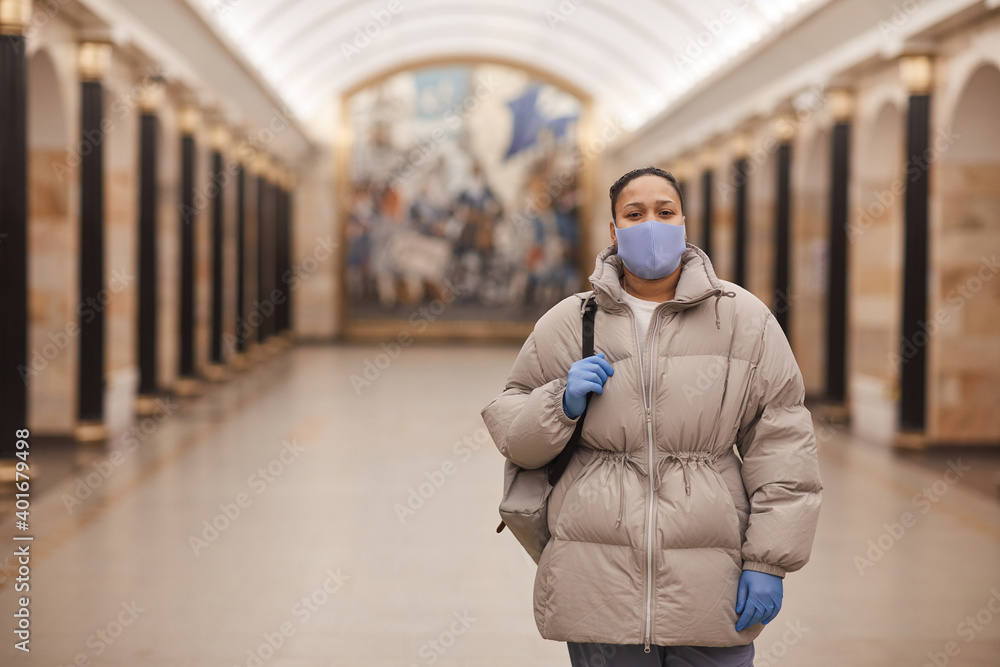 Naklejka premium Portrait of woman in warm clothing and in protective wear looking at camera while walking in pandemic