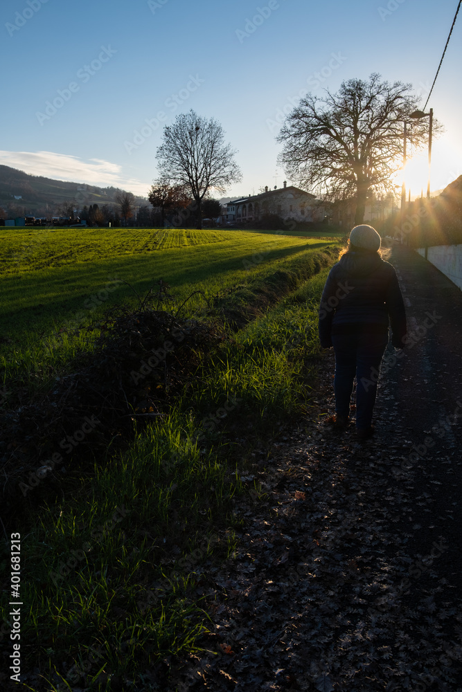 Donna controluce che cammina sul sentiero in collina Donna controluce che cammina sul sentiero in collina