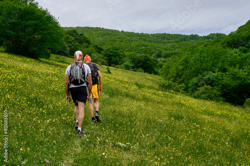 Young friends boys and girls walk in the mountains, along paths trought rocks and nature. 