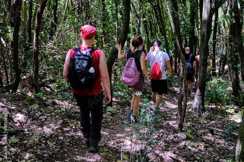 Young friends boys and girls walk in the mountains, along paths trought rocks and nature. 