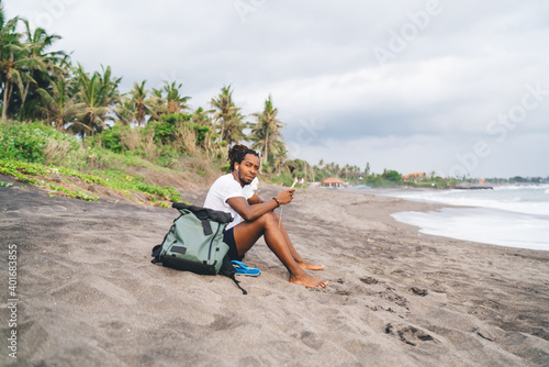 Black man sitting on sandy beach
