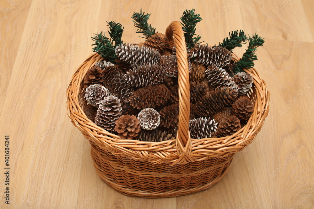 rustic handmade basket with pine cones on wooden background