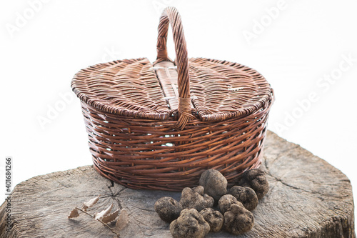Some black truffles and a basket and a leaf.