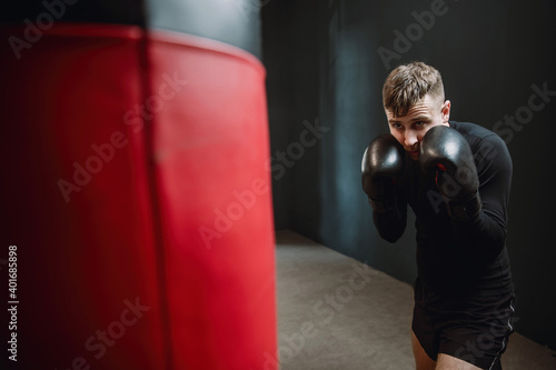 A man boxer beats a punching bag. Boxer practicing punches in the ring. The athlete strikes with a punching bag. 4k video © Chiheisen