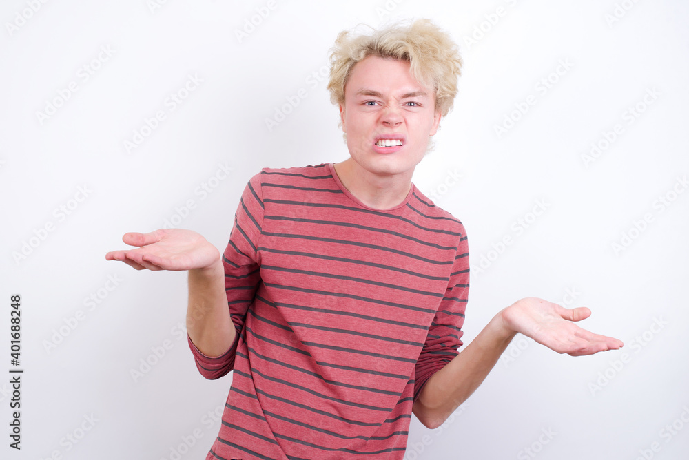 Clueless Young handsome Caucasian blond man standing against white background shrugs shoulders with hesitation, faces doubtful situation, spreads palms, Hard decision Clueless Young handsome Caucasian blond man standing against white background shrugs shoulders with hesitation, faces doubtful situation, spreads palms, Hard decision