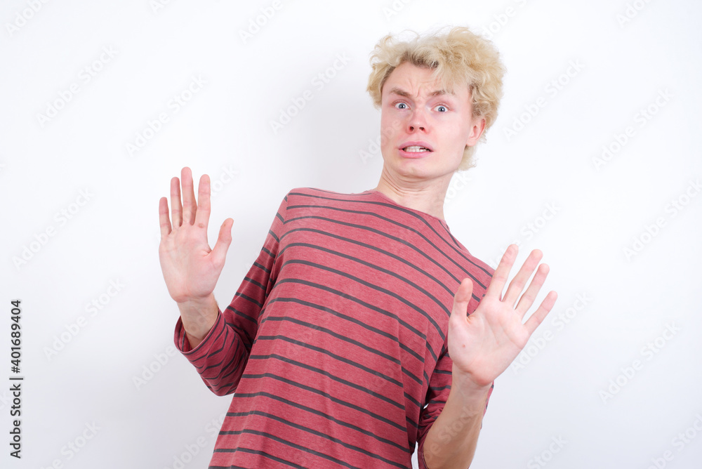 Young handsome Caucasian blond man standing against white background afraid and terrified with fear expression stop gesture with hands, shouting in shock. Panic concept. Young handsome Caucasian blond man standing against white background afraid and terrified with fear expression stop gesture with hands, shouting in shock. Panic concept.