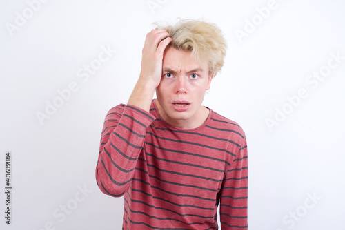 Embarrassed Young handsome Caucasian blond man standing against white background with shocked expression, expresses great amazement, Puzzled model poses indoor