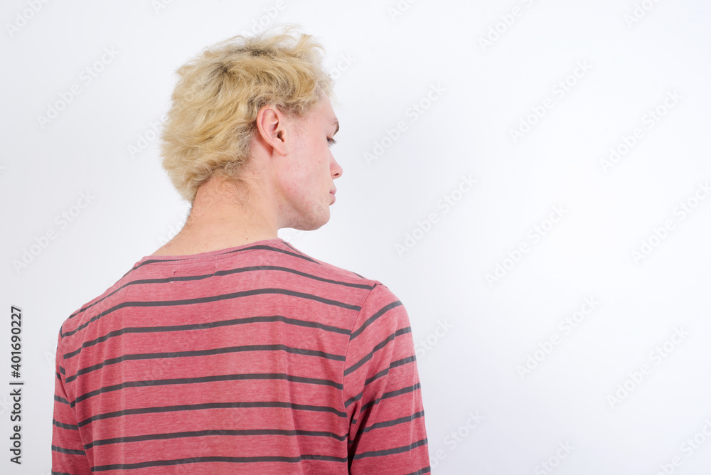 The back side view of a Young handsome Caucasian blond man standing against white background. Studio Shoot. The back side view of a Young handsome Caucasian blond man standing against white background. Studio Shoot.