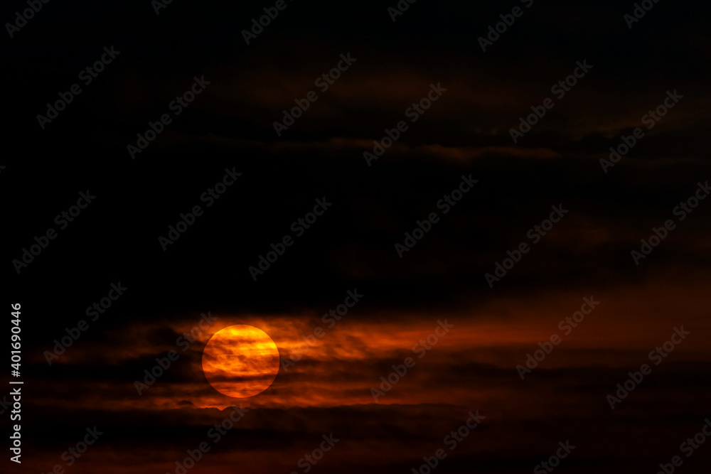 A rising sun shows through dark clouds. A rising sun shows through dark clouds.