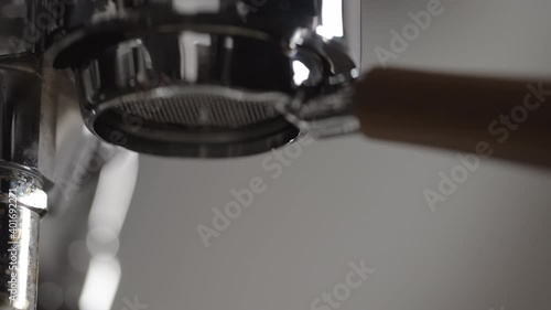 Slow motion low angle shot of espresso extraction from naked portafilter into white cup photo