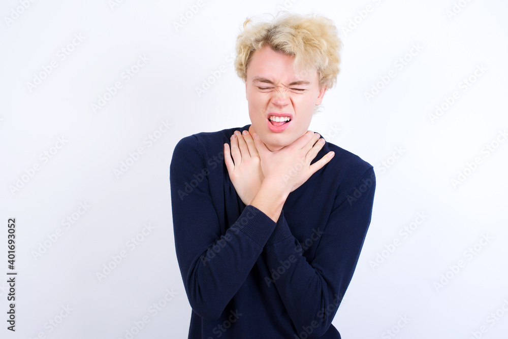 Young handsome Caucasian blond man standing against white background shouting suffocate because painful strangle. Health problem. Asphyxiate and suicide concept. Young handsome Caucasian blond man standing against white background shouting suffocate because painful strangle. Health problem. Asphyxiate and suicide concept.