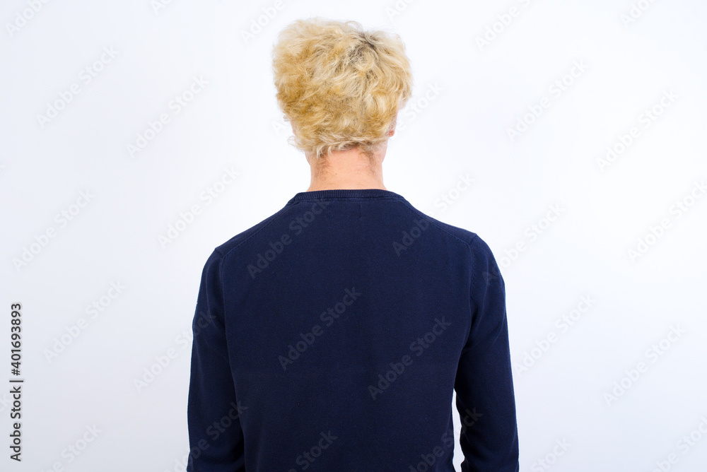 The back view of a Young handsome Caucasian blond man standing against white background. Studio Shoot. The back view of a Young handsome Caucasian blond man standing against white background. Studio Shoot.
