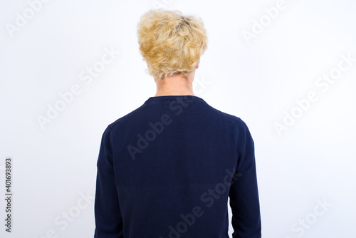 The back view of a Young handsome Caucasian blond man standing against white background. Studio Shoot.