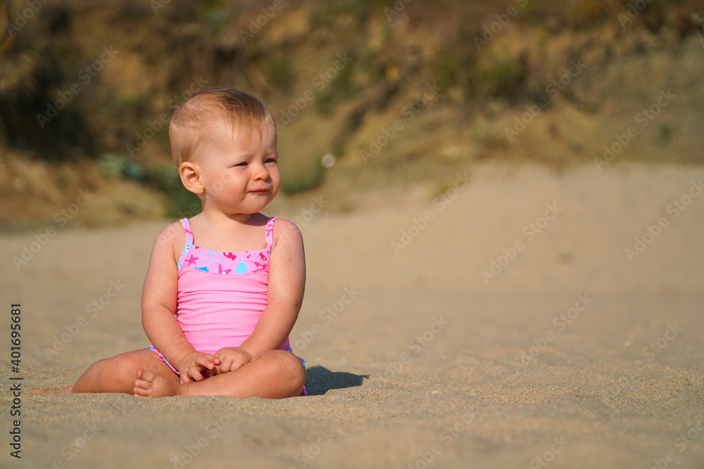 Happy baby in the sand plays. Cheerful little kid playing on the beach on a sunny day. High quality photo Happy baby in the sand plays. Cheerful little kid playing on the beach on a sunny day. High quality photo