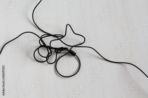 Black tangled headphone wires on white background