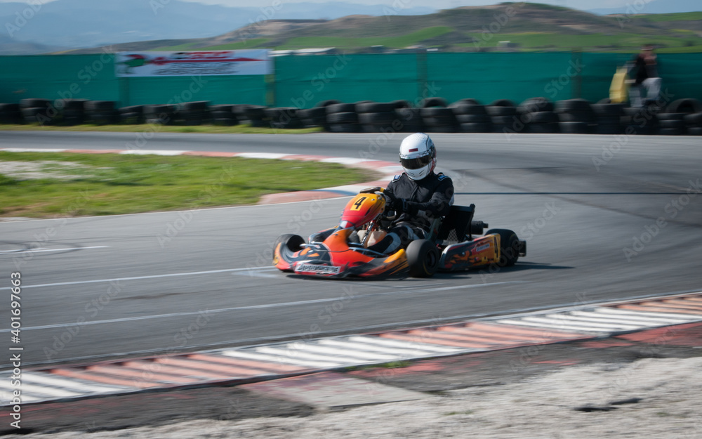 Unrecognised man driving Go-kart with speed in the on a karting track - obrazy, fototapety, plakaty 