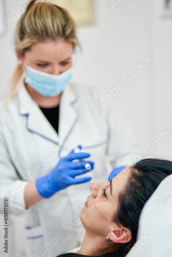 Close up of hands of cosmetologist making injection.