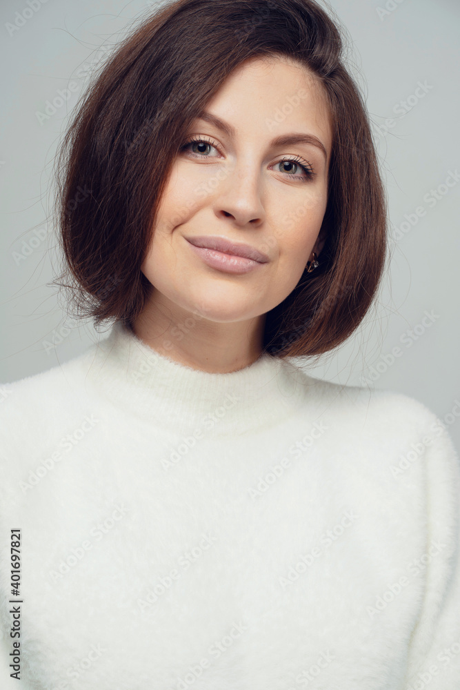 portrait of a serious confident young woman brunette 20-30 years of Caucasian appearance, looking at the camera smiling. White warm stylish jacket portrait of a serious confident young woman brunette 20-30 years of Caucasian appearance, looking at the camera smiling. White warm stylish jacket