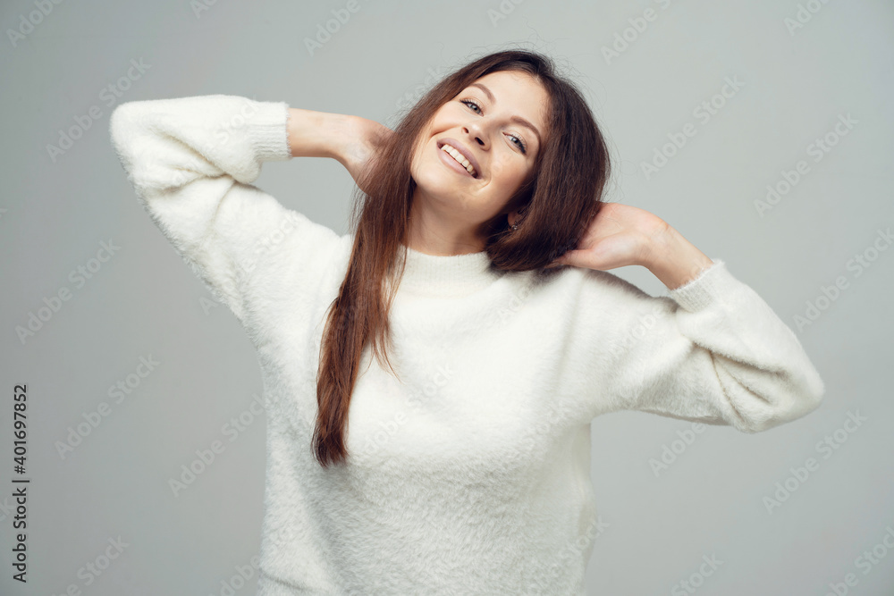 woke up stretches shows a hand gesture to the side. portrait face smiling young brunette woman of caucasian appearance. looking at the camera, posing in a photo studio on a gray background. woke up stretches shows a hand gesture to the side. portrait face smiling young brunette woman of caucasian appearance. looking at the camera, posing in a photo studio on a gray background.