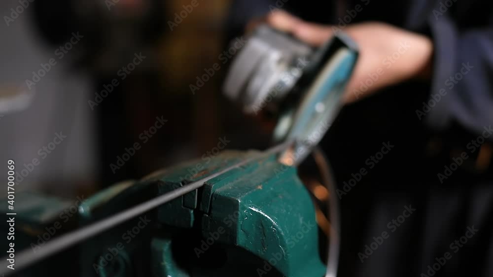 Selective focus of iron rod clamped in machine while woman using electric hand welding machine to join and sharpen ends in workshop Selective focus of iron rod clamped in machine while woman using electric hand welding machine to join and sharpen ends in workshop