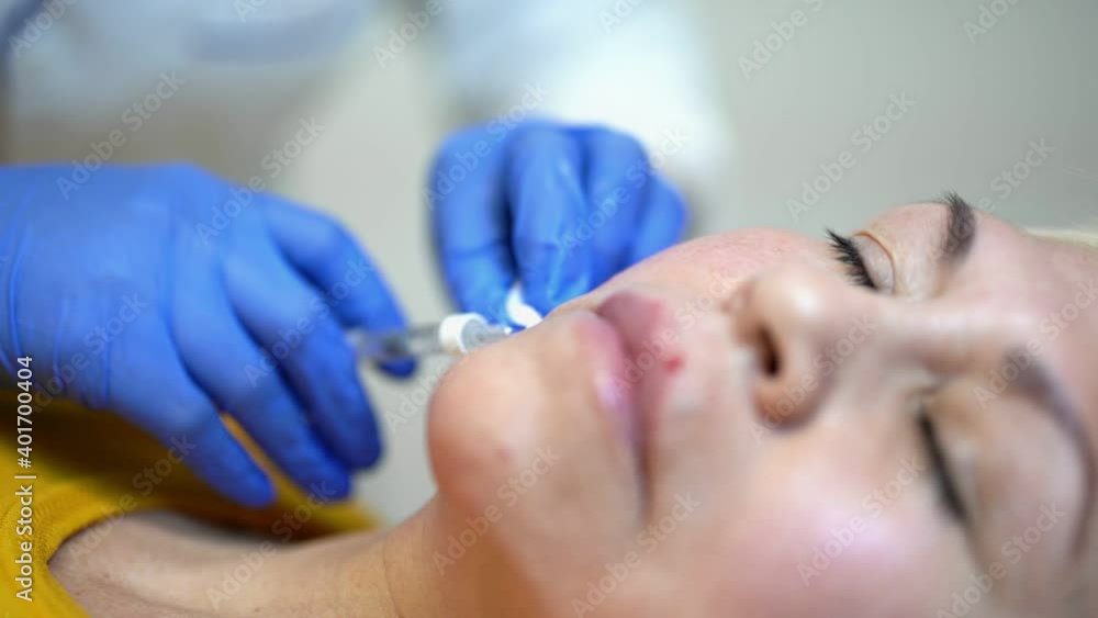 Close up of hands of cosmetologist making botox injection. She is holding syringe. Woman is receiving procedure with enjoyment Close up of hands of cosmetologist making botox injection. She is holding syringe. Woman is receiving procedure with enjoyment