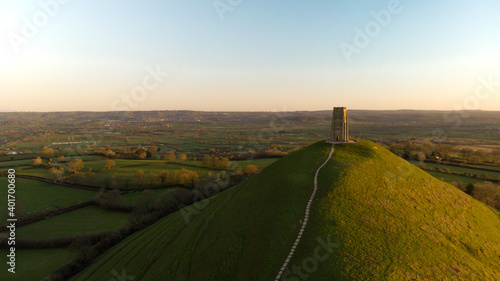 Fotografie Aerial view of the early morning sunrise over Glastonbury Tor with Somerset fields below