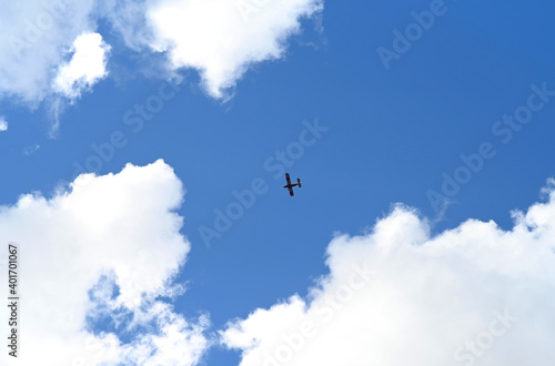 A small silhouette of an airplane in a blue sky with clouds