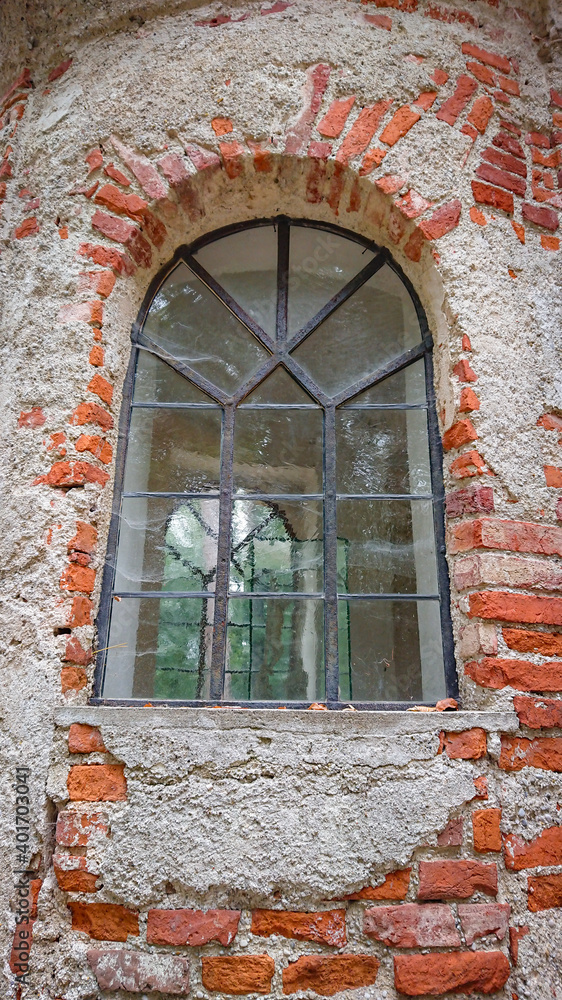 Window of an abandoned temple built of brick. Time destroyed the outer plaster. Time flow symbol