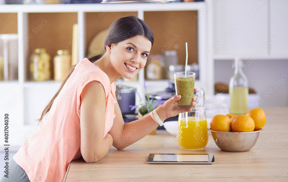 Beautiful young woman using a digital tablet in the kitchen Beautiful young woman using a digital tablet in the kitchen